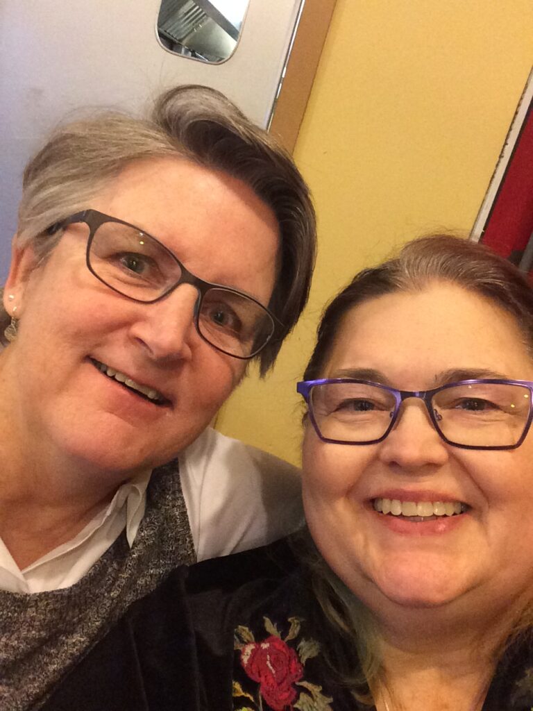 Two women smiling and posing together for the camera, showcasing a joyful moment.